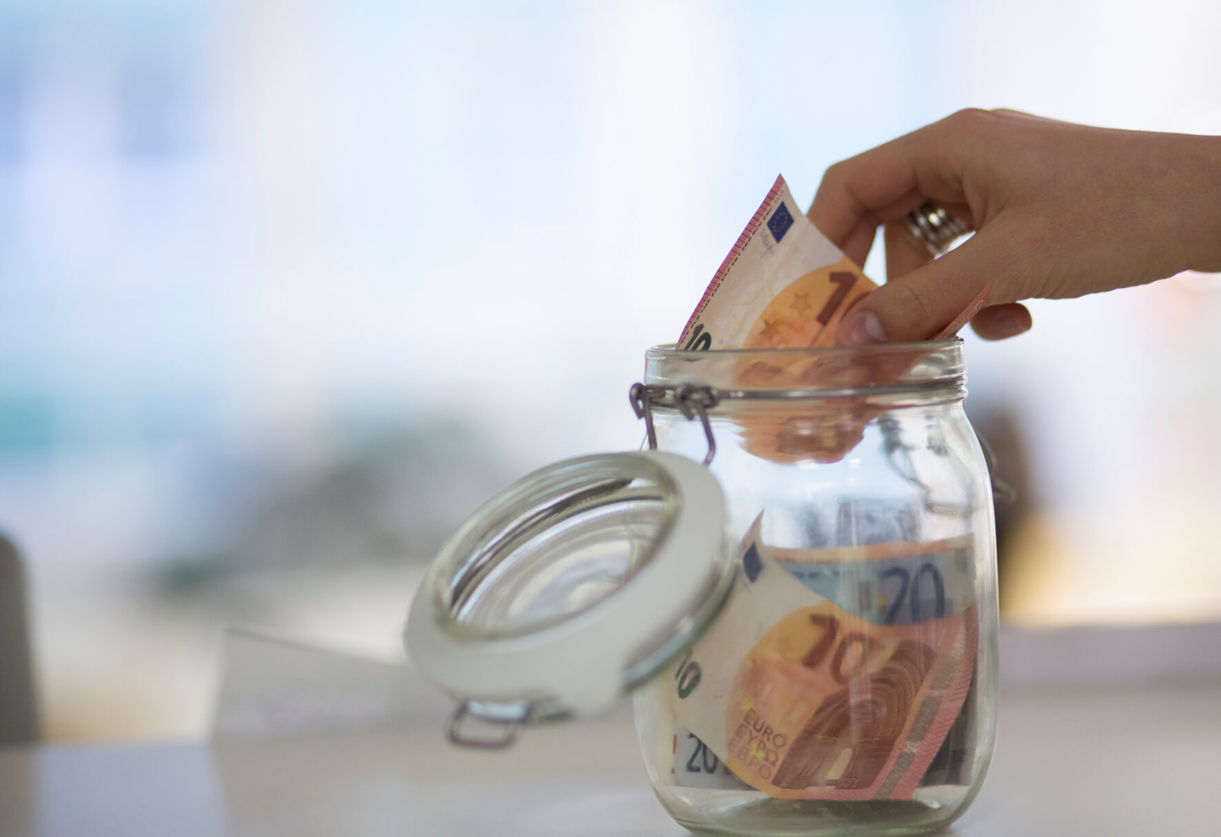 Hand mit Geld in Einweckglas