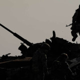 A Ukrainian serviceman walks on a destroyed Russian fighting vehicle in Bucha, Ukraine, Thursday, April 7, 2022
